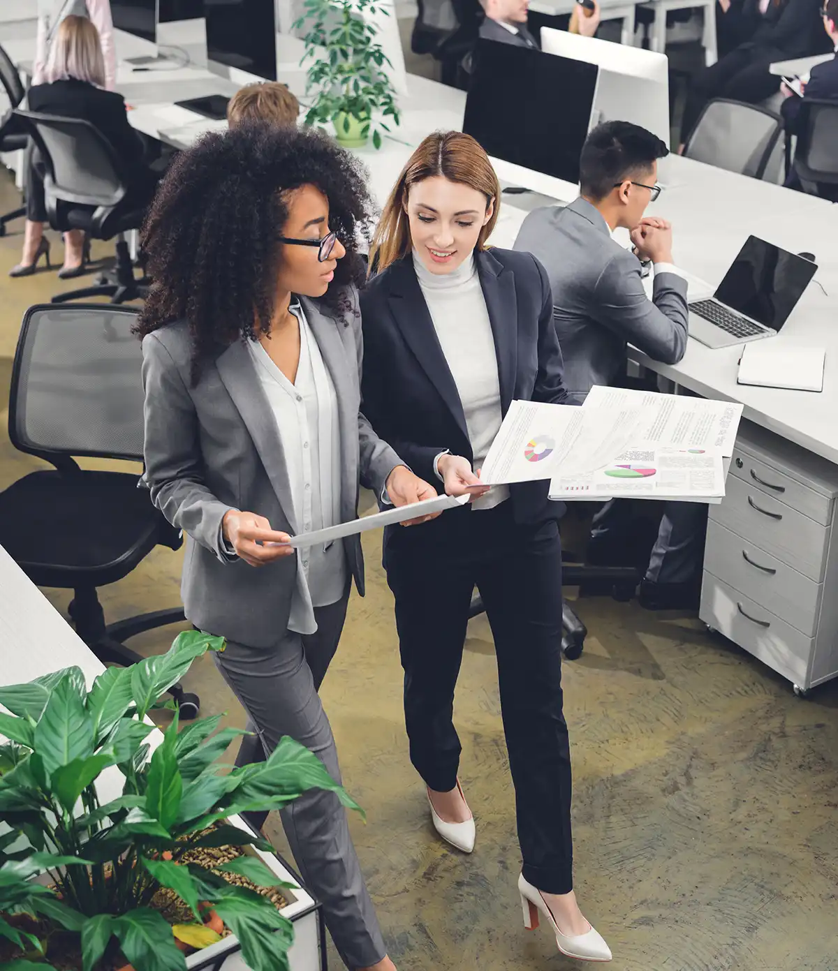 high angle view of professional young businesswomen holding papers and discussing project in office